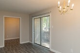Located at 1719 Fairfax Rd in Greensboro, NC, this single-story home presents a clean, updated interior finished in a consistent neutral color palette throughout. Gray-toned laminate wood flooring runs through the main living areas and bedrooms, providing a cohesive and low-maintenance foundation underfoot. White trim and baseboards complement the warm beige walls, creating a bright and welcoming atmosphere.

The spacious main living area offers generous room for furnishings, with multiple doorways providing connectivity to the rest of the home. The kitchen is equipped with white cabinetry, gray laminate countertops, a stainless steel sink, a dishwasher, an electric range, and a refrigerator, all supported by ample upper and lower cabinet storage.

The bedrooms are well-proportioned, each featuring laminate flooring and natural light from windows fitted with blinds. Storage is well-considered, with built-in closets and shelving units visible in several rooms. One bedroom notably includes both a walk-in closet and an additional arched built-in shelving niche.

The bathroom includes a full tub and shower combination with white tile surround and chrome fixtures. A dedicated laundry area with utility hookups and an electrical panel provides added practicality. Overall, the home offers a functional, move-in ready layout suitable for everyday living.