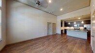 This single-floor residence offers a thoughtfully designed open layout with impressive architectural details throughout. The main living area features soaring ceilings, rich hardwood-style flooring, and ceiling fans, creating an airy and comfortable atmosphere. A dedicated entryway with a transom window welcomes natural light into the space.

The kitchen is a standout feature, showcasing dark espresso cabinetry extending to the ceiling with under-cabinet lighting, light granite countertops, a breakfast bar island, and a full suite of stainless steel appliances including a side-by-side refrigerator, electric range, and built-in microwave.

The primary bedroom is generously proportioned with plush carpeting, a ceiling fan, and direct access to an en-suite bathroom. The primary bath features a granite-topped vanity with dark cabinetry, hardwood-style flooring, a walk-in glass-enclosed shower, and a separate soaking tub with floor-to-ceiling tile surround. A spacious walk-in closet with built-in shelving and hanging rods provides ample storage.

The secondary bedroom is bright and comfortable, fitted with carpet, a ceiling fan, and a large window offering natural light and outdoor views. A second full bathroom includes a tub-shower combo with tiled surround. The home's neutral palette and quality finishes create a cohesive, move-in ready environment throughout.