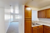 Located at 801 Magnolia Ave in Corona, California, this single-floor residence offers a practical and well-organized layout with two bedrooms and two bathrooms. The kitchen is equipped with warm honey-toned wood cabinetry, granite-style countertops, a double-basin sink, and a white electric range, all set on light hardwood-style flooring. A pass-through window connects the kitchen to the living area, which features a ceiling fan and soft carpeting throughout. The living space flows naturally into a hallway that leads to the bedrooms and bathrooms. Both bedrooms are carpeted and filled with natural light from exterior-facing windows, offering a calm and comfortable atmosphere. The primary bedroom is a generous size and benefits from ample closet space, including a walk-in closet outfitted with multiple wire shelving units and hanging rods. Two additional closets provide further storage throughout the unit. The two bathrooms feature wood-toned vanities with granite-style countertops, large mirrors, and light hardwood-style flooring. White walls and clean finishes are consistent throughout the home, creating a bright, neutral interior that is easy to personalize.