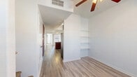 This two-story residence offers a thoughtfully designed layout that balances functionality and comfort across both levels. The main living area features soaring ceilings, light-toned hardwood-style flooring, and a built-in shelving unit that adds both character and practical storage. A ceiling fan overhead enhances the airy feel of the space, while a sliding glass door floods the room with natural light and provides access to an outdoor area.

The kitchen is well-equipped and centrally positioned, featuring rich cherry-toned cabinetry, light countertops, and a suite of black Whirlpool appliances including a gas range, over-the-range microwave, dishwasher, and refrigerator. A peninsula with a double-basin sink creates a convenient workspace and casual dining option, while a pendant light adds a finishing touch overhead.

The bedrooms are carpeted for warmth and comfort, each outfitted with ceiling fans and windows fitted with blinds for natural light control. The bathrooms are finished with matching cherry-toned vanity cabinetry, light countertops, and hardwood-style flooring. One bathroom offers convenient proximity to an in-unit washer and dryer. A central staircase connects the two floors, making the layout practical and easy to navigate throughout.