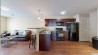Located at 258 University Dr in Marion, Ohio, this single-floor unit offers a well-organized layout designed for comfortable everyday living. The open-concept kitchen and living area form the heart of the space, where rich dark-cabinetry kitchen is equipped with black appliances including a gas range, built-in microwave, and full-size refrigerator. Granite-style countertops extend to a peninsula with bar seating, illuminated by pendant lighting overhead. The kitchen flows directly into the living area, which features warm hardwood-style flooring and large windows that invite natural light.

The living room provides a comfortable, functional space with ample room for seating and features additional windows for natural light. Each bedroom includes built-in drawer storage beneath the bed frame, a dedicated desk area, and carpeted flooring for comfort. One bedroom benefits from dual windows, enhancing brightness throughout the day.

The bathrooms are finished with hardwood-style flooring, dark wood vanities with granite-style countertops, and a full tub-shower combination. A louvered closet door near the kitchen adds practical storage. The overall palette of warm neutrals and dark wood tones creates a cohesive and inviting atmosphere throughout the unit.