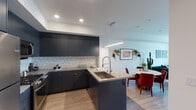 This well-appointed one-bedroom, one-bathroom residence in Long Beach, California offers a thoughtfully designed open floor plan with contemporary finishes throughout. Light wood-style flooring runs continuously across the living areas, contributing to a cohesive and modern aesthetic.

The kitchen is a standout feature, equipped with matte navy cabinetry extending to the ceiling, stainless steel appliances including a gas range, microwave, and full-size refrigerator, and a geometric white tile backsplash. A peninsula with a deep basin sink and neutral quartz-style countertops provides additional workspace and casual seating, seamlessly connecting to the dining area.

The living room is bright and inviting, with French doors opening to a private balcony that offers elevated views of the surrounding Long Beach cityscape. Natural light fills the space, enhancing the clean, open feel.

The bedroom features large windows framing city views, a soft blue accent wall, and ample room for furnishings. A second window configuration provides cross ventilation and additional light.

The bathroom is finished with vertically stacked white subway tile in the tub-shower surround, warm wood-tone flooring, and clean white walls, creating a fresh and functional space.