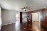 Located at 1125 SW Fourth Pl in Gainesville, FL, this single-story, 3-bedroom, 3-bathroom home offers a functional and comfortable layout. Rich, dark hardwood floors run throughout most of the home, lending warmth and character to the living spaces. The living room greets you at the entry with a ceiling fan, natural light from front-facing windows, and a welcoming front door with a transom window above.

The kitchen is well-appointed with white cabinetry, bold red countertops, white appliances, and hardwood flooring. An adjacent dining or prep area features arched architectural details, extended counter space, and large windows overlooking the outdoors, flooding the space with natural light.

Each of the three bedrooms features hardwood floors, windows with blinds, and dedicated closets outfitted with wire shelving systems. The spacious primary bedroom includes multiple windows and a walk-in closet with built-in shelving and tile flooring. The three bathrooms each include a tiled tub-shower combination with a curved curtain rod and neutral beige tile surround. A hallway connects all rooms, providing a logical and efficient flow throughout the home.