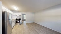 This single-floor unit offers a thoughtfully updated interior with a clean, modern aesthetic throughout. Light-toned wood-look flooring runs consistently across the living areas, creating a cohesive and easy-to-maintain finish. The open-concept layout connects the kitchen and living area seamlessly, maximizing the sense of space.

The kitchen is well-appointed with white shaker-style cabinetry, granite-look countertops, a classic white subway tile backsplash, and a full suite of stainless steel appliances including a refrigerator, electric range, and ventilation hood. A double-basin sink and ample cabinet storage make it both functional and visually appealing.

The living area is generously proportioned with smooth white walls and large windows that allow natural light to filter in, offering views of surrounding greenery. The bedroom continues the wood-look flooring and features a ceiling fan with light fixture, a window with blinds for natural light and privacy, and direct access to the bathroom.

The bathroom presents a clean, bright finish with white subway tile, a single-sink vanity with white cabinetry, brushed nickel fixtures, a walk-in shower, and a window for added ventilation. Overall, the space maintains a fresh, move-in-ready condition with a neutral palette throughout.