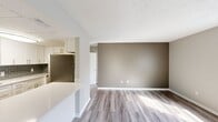 This efficiently designed 2-bedroom, 1-bathroom unit is laid out on a single floor, making effective use of its compact footprint. The galley-style kitchen is a standout feature, outfitted with white shaker cabinetry accented by brushed nickel hardware, white quartz countertops, and a gray subway tile backsplash. A full suite of stainless steel appliances — including a range, over-the-range microwave, refrigerator, and dishwasher — provides modern functionality. Wood-look luxury vinyl plank flooring runs consistently throughout the unit, lending a cohesive and contemporary feel.

The open living area transitions naturally from the kitchen, offering a neutral color palette with taupe accent walls and ample room for everyday living. Both bedrooms are finished with the same flooring and soft gray walls. The primary bedroom includes a built-in closet with a rod and shelf system. The secondary bedroom features a window that brings in natural light. A shared full bathroom includes a single-sink vanity with dark countertop, white cabinetry, a large mirror, and a tub-shower combination. Textured ceilings are present throughout the unit.