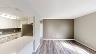This efficiently designed 2-bedroom, 1-bathroom unit is laid out on a single floor, making effective use of its compact footprint. The galley-style kitchen is a standout feature, outfitted with white shaker cabinetry accented by brushed nickel hardware, white quartz countertops, and a gray subway tile backsplash. A full suite of stainless steel appliances — including a range, over-the-range microwave, refrigerator, and dishwasher — provides modern functionality. Wood-look luxury vinyl plank flooring runs consistently throughout the unit, lending a cohesive and contemporary feel.

The open living area transitions naturally from the kitchen, offering a neutral color palette with taupe accent walls and ample room for everyday living. Both bedrooms are finished with the same flooring and soft gray walls. The primary bedroom includes a built-in closet with a rod and shelf system. The secondary bedroom features a window that brings in natural light. A shared full bathroom includes a single-sink vanity with dark countertop, white cabinetry, a large mirror, and a tub-shower combination. Textured ceilings are present throughout the unit.