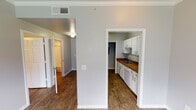 Located at 915 Desco Ln in Grand Prairie, Texas, this single-floor unit offers a clean, functional layout designed for comfortable everyday living. Throughout the space, warm wood-look flooring creates a cohesive and inviting atmosphere, complemented by cool gray walls and crisp white trim and crown molding.

The galley-style kitchen is well-appointed with abundant white cabinetry, rich brown countertops, a stainless steel sink, and white appliances including a range, refrigerator, and microwave. A pass-through opening connects the kitchen to the main living area, enhancing the sense of flow between spaces.

The living and dining areas are open and airy, with a ceiling fan providing comfort and a window allowing natural light to filter in. Additional rooms — ideal for use as bedrooms or flex spaces — feature ceiling fans, crown molding, and windows with blinds that bring in exterior views and natural light.

The bathroom is neatly finished with a white vanity, a framed mirror with overhead vanity lighting, and a tiled tub-and-shower combination. The overall design is consistent and well-maintained, with neutral tones throughout that create a versatile backdrop for any furnishing style. The single-floor layout ensures easy accessibility and efficient use of space.