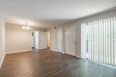 Located at The Pines in Jackson, Mississippi, this single-floor unit offers a practical and comfortable layout throughout. The living area is generously sized, featuring durable wood-look flooring, neutral-toned walls, and a chandelier light fixture that adds a classic touch. A vertical blind-covered sliding glass door floods the space with natural light and provides access to an outdoor patio area, enhancing the open feel of the room.

The kitchen is efficiently designed with warm oak cabinetry, dark countertops, and a double basin sink positioned beneath a window that brings in additional natural light. Appliances are included, and the layout maximizes counter and storage space for everyday use.

The bedrooms are carpeted for comfort, each equipped with a ceiling fan for year-round climate control. One bedroom features a large window with views of the surrounding greenery, while another includes built-in closet shelving, offering practical storage solutions. An additional room with wood-look flooring and subtle panel-style wall detailing provides flexibility as a bedroom or office space.

The bathroom includes a full tub-shower combo with classic white tile surround, a vanity with granite-style countertops, white cabinetry, and wood-look flooring, completing this well-appointed unit.