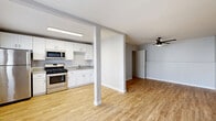 Located at 1133-1137 27th St in San Diego, CA, this one-bedroom, one-bathroom unit offers a thoughtfully designed layout that maximizes every square foot. Light-toned hardwood-style flooring runs throughout the space, creating a cohesive and clean aesthetic. The open living area is bright and airy, benefiting from natural light streaming through front-facing windows, and is equipped with a modern ceiling fan with integrated lighting. A structural column defines the transition between the living area and the kitchen, adding architectural character without enclosing the space. The kitchen features white shaker-style cabinetry, gray countertops, a stainless steel sink, and a full suite of stainless steel appliances including a gas range, microwave, and refrigerator. The generously sized bedroom comfortably serves as the primary retreat, also fitted with a ceiling fan and direct access to the rest of the unit. The bathroom is a standout feature, showcasing large-format stone-look tile in the walk-in shower, mosaic tile flooring, a white vanity with an undermount sink, and chrome hardware and shelving accents. Clean gray walls and white trim throughout contribute to a fresh, modern ambiance well-suited for comfortable everyday living.