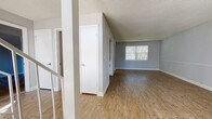 This two-floor home is designed with a clean, functional layout that makes efficient use of its space across both levels. The main living area features wood-look flooring in a warm, natural tone, complemented by light gray walls and crisp white trim throughout. A textured ceiling adds character, while windows allow natural light to fill the open living space. The staircase connects the two floors and is visible from the main living area, contributing to the home's open feel.

The galley-style kitchen is outfitted with white shaker cabinetry, light granite-style countertops, and black appliances including a range and refrigerator, offering a practical and stylish cooking space that opens toward the living area.

The bathrooms feature wood-look flooring, with one bath including a tub-shower combination with white tile surround. Neutral gray walls and brushed nickel hardware provide a cohesive, modern finish.

The bedrooms are carpeted in a neutral tone, providing comfort underfoot. The primary bedroom is generously sized and includes mirrored closet doors with built-in shelving and rod storage, as well as a private en-suite bath and access to a balcony. Additional bedrooms offer ample space and natural light, making this a well-rounded and move-in ready home.