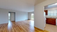 This single-floor residence at 1-20 Scott Court offers a well-organized layout spread across a thoughtfully designed living space. Warm-toned hardwood flooring runs throughout the main living areas and bedrooms, lending a cohesive and inviting character to the interior.

The main living area is generously proportioned, featuring neutral white walls, baseboard heating, and a sliding glass door that opens onto a private balcony overlooking greenery — allowing natural light to fill the room throughout the day. The open feel of this space makes it highly versatile for various furniture arrangements.

The kitchen is equipped with rich, warm-toned wood cabinetry, granite-look countertops, a built-in dishwasher, and a window that brings in additional natural light. The space is practical and well-appointed for everyday use.

The bedroom features hardwood flooring, a window-mounted air conditioning unit, a large multi-pane window with outdoor views, and a closet conveniently located near the entry door.

The bathroom is finished with floor-to-ceiling marbled tile surrounding the tub-shower combination, a white vanity with storage, tile flooring, and a frosted window for privacy. Baseboard heating is present throughout the unit, ensuring comfort year-round.