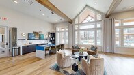 Located at 375 Greenbriar Rd in Fate, TX, this thoughtfully designed community clubhouse offers a generous, open floor plan across a single level. The space is anchored by soaring vaulted ceilings with exposed wood beams and floor-to-ceiling windows that flood the interior with natural light and frame views of the outdoor pool area. Light hardwood flooring runs throughout, tying together the various zones seamlessly.

The main lounge area features a dramatic gabled window wall, dual ring pendant chandeliers, and plush navy velvet seating alongside a built-in desk workstation. Adjacent to it, a stylish social lounge showcases a bold blue kitchen island with bar seating and dark cabinetry with subway tile backsplash. A cozy entry corridor greets visitors with patterned wallcovering, a built-in upholstered bench, and curated artwork.

A dedicated entertainment lounge includes a striking chevron-patterned wood accent wall with a mounted TV, a circular pendant light, and richly colored seating. The game room provides a pool table, shuffleboard, a large marble-effect feature wall with TV, and ample natural light. A compact cyber lounge offers a built-in desk with multiple workstations overlooking the pool courtyard, ideal for remote work or study.