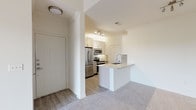 This 2-bedroom, 2-bathroom single-story residence offers a thoughtfully designed layout that balances functionality and comfort. The entryway opens directly to the kitchen and living area, establishing a practical flow throughout the space.

The kitchen is a standout feature, equipped with stainless steel appliances including a refrigerator, range, and microwave. White cabinetry with brushed nickel hardware pairs with granite countertops and a subtle tile backsplash in a neutral tone. A peninsula with an undermount sink provides additional prep space and serves as a natural divider between the kitchen and the adjoining living area. Light wood-style flooring runs throughout the kitchen, complementing the bright, clean aesthetic.

The living area is generously proportioned, featuring soft carpeting, a ceiling fan, and a sliding glass door that allows natural light and outdoor views. The two bedrooms are carpeted and well-sized, with one room featuring a ceiling fan and a window fitted with horizontal blinds. Crown molding adds a refined detail in the secondary bedroom.

Both bathrooms feature tub-shower combinations with white tile surrounds and wood-style flooring, maintaining a consistent, clean design throughout. The overall ambiance of the residence is light, neutral, and move-in ready.