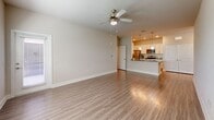 Located in Tavares, FL, this single-story, one-bedroom, two-bathroom residence offers a well-designed open-concept layout with consistent wood-look flooring throughout. The combined kitchen and living room forms the heart of the home, where a spacious, bright living area with a ceiling fan opens directly to a well-appointed kitchen. The kitchen features white shaker-style cabinetry, granite countertops, stainless steel appliances including a refrigerator, electric range, microwave, and dishwasher, as well as pendant lighting above a breakfast bar peninsula. A separate dining room provides additional space for entertaining. The generously sized primary bedroom includes a ceiling fan, natural light from a window with blinds, and access to two closets equipped with wire shelving systems for organized storage. The two bathrooms are finished with granite-topped vanities and wood-look flooring; one includes a full tub-shower combination with clean white tile surround. Additional functional spaces include a dedicated laundry area, a utility room, a hallway connecting the living spaces, and a patio for outdoor enjoyment. The interior presents a clean, neutral color palette with bright white trim throughout, lending the home a fresh and modern ambiance.