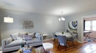 This two-floor residence at The Gardens at Raritan presents a well-organized layout with a cohesive, contemporary aesthetic throughout. The main living area welcomes residents with warm hardwood flooring, soft gray walls, and natural light streaming through draped windows. The open arrangement connects the living room to a dedicated dining area, where a modern chandelier illuminates a round table and contemporary seating. Tasteful wall art adds personality to both spaces.

The kitchen is equipped with warm oak cabinetry, granite-style countertops, a stainless steel sink, and black appliances including a gas range and over-the-range microwave. A window above the counter brings in natural light.

The residence includes multiple bedrooms, each featuring hardwood floors, ceiling fans with light fixtures, and windows dressed with curtain panels. The primary bedroom offers dual windows and ample space, while a secondary bedroom maintains a similarly comfortable scale. A dedicated home office space provides a bright, functional area with framed artwork and natural light from a large window.

The bathroom features tile surround in warm neutral tones with a mosaic accent border, a soaking tub with shower, and clean, classic fixtures. Overall, the home offers a balanced blend of function and style across its two floors.