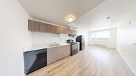 Located at 409 S 23rd St in Tacoma, WA, this one-bedroom, one-bathroom unit offers a well-designed layout that maximizes its compact footprint. Light wood-style flooring runs throughout, lending warmth and continuity to the space, while crisp white walls create a bright, clean aesthetic.

The kitchen is a functional highlight, featuring warm-toned wood cabinetry extending to the upper walls for ample storage, white countertops, a stainless steel sink, and a full suite of black appliances including an electric range, dishwasher, and refrigerator. A bold teal entry door adds a touch of personality to the space.

The bedroom is a comfortable, well-proportioned room with a window that allows natural light to fill the space, complemented by a baseboard heater for year-round comfort. The room's clean lines and neutral palette provide a versatile canvas.

The bathroom is finished with light wood-toned cabinetry, a white countertop vanity, a large mirror with overhead lighting, and durable wood-style flooring that ties back to the rest of the unit.

A hallway connects the rooms efficiently, and the overall layout—as illustrated by the 3D floor plan—makes thoughtful use of every square foot. This unit offers a modern, move-in-ready living environment in the heart of Tacoma.