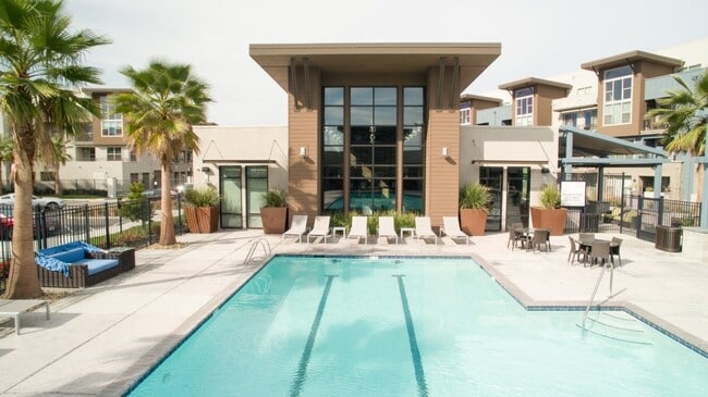 Aspire Apartments Tracy California Luxury Living A large swimming pool in front of a building with palm trees. - Aspire Apartments