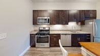 Located at 380 Mather St in Hamden, CT, this well-appointed 2-bedroom, 2-bathroom residence offers a thoughtfully designed single-level layout. Hardwood-style flooring flows consistently throughout the space, lending a warm, cohesive aesthetic to every room.

The combined kitchen and living area serves as the heart of the home. The kitchen is outfitted with rich dark-espresso cabinetry, granite countertops, and a full suite of stainless steel appliances including a gas range, microwave, dishwasher, and refrigerator — providing both style and functionality.

The living area connects seamlessly to a private outdoor access point through a glass-paneled door, allowing natural light to fill the space. Both bedrooms are generously proportioned, featuring large windows that frame outdoor views and bathe the rooms in natural light. The spacious primary bedroom includes access to a well-sized walk-in closet with wire shelving and hanging rods. A second walk-in closet provides additional storage convenience.

The two bathrooms are clean and modern, with one featuring a full tub-shower combination with chrome fixtures and a dark-cabinet vanity with a light countertop. Neutral wall tones throughout the residence create a calm, move-in-ready ambiance suitable for a variety of interior styles.