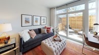 This well-appointed 2-bedroom, 2-bathroom home with a nook offers a thoughtfully designed single-floor layout filled with natural light. The living area features floor-to-ceiling sliding glass doors that open directly onto a private outdoor patio enclosed by warm cedar wood fencing, creating a seamless indoor-outdoor connection. The nook, adjacent to the living space, provides a flexible area ideal for a home office or reading corner, also benefiting from patio access and ample light.

The kitchen is outfitted with sleek white cabinetry, quartz countertops, a marble-style tile backsplash, and a full suite of stainless steel appliances, including a gas range, dishwasher, and built-in microwave. Light wood-tone flooring runs throughout the main living and kitchen areas, lending a clean, contemporary feel.

Both bedrooms are carpeted and receive generous natural light through large windows with views of the surrounding neighborhood. The primary bedroom is spacious enough to accommodate a four-poster bed and additional furnishings. Each bathroom is finished with light wood-tone cabinetry, wide vanity mirrors, and classic white subway tile in the tub and shower surrounds, complemented by light tile flooring for a bright, modern aesthetic.