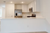 This contemporary single-story residence offers 1420 square feet of thoughtfully designed living space. The home boasts four bedrooms, including a spacious 160 square foot primary bedroom, and two full bathrooms. The heart of the home is an open-concept living area that seamlessly integrates the kitchen and living room, creating an ideal space for both everyday living and entertaining.

The kitchen is a highlight, featuring sleek white cabinetry, stainless steel appliances, and a functional layout with ample counter space. Light-toned flooring throughout the common areas adds to the bright, airy feel of the home. The bathrooms are modern and well-appointed, with one showcasing a walk-in shower with built-in shelving.

Bedrooms are generously sized and carpeted for comfort, with the primary bedroom offering additional space for a relaxing retreat. The neutral color palette used throughout the home provides a blank canvas for personalization. Large windows in various rooms allow for natural light to flood the space, enhancing the open and inviting atmosphere.

Additional features include recessed lighting, a separate laundry area, and a closet for extra storage. The property's efficient use of space and contemporary design elements make it an attractive option for those seeking a modern, low-maintenance home in San Antonio.