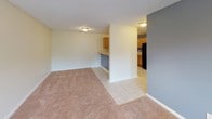 This single-floor 1-bedroom, 1-bathroom unit offers a practical and comfortable layout designed for everyday living. The living area features warm, neutral-toned carpet, a ceiling fan with integrated lighting, and access through French doors that invite natural light into the space. The open layout connects the living area to the kitchen through a half-wall breakfast bar, creating a welcoming flow between rooms.

The kitchen is equipped with warm oak cabinetry, ample upper and lower storage, generous L-shaped countertops, tile flooring, and black appliances including an electric range and over-the-range microwave. A distinctly accented gray wall adds a modern touch to the kitchen's color palette.

The bedroom is a comfortable, carpeted room with a ceiling fan, natural light from a window with blinds, and textured ceilings — providing a calm and restful atmosphere.

The bathroom is a standout feature of this unit, showcasing a large jetted soaking tub with a tiled surround accented by a bold blue-and-black checkered tile border. A separate shower area, single-basin vanity with oak cabinetry, a large mirror, and a small privacy window complete the space. Tile flooring ties the room together for a clean, cohesive look throughout.