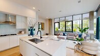 Located at 3130 Potomac Ave in Arlington, VA, this two-story residence offers a thoughtfully designed layout across two generously sized floors. The main level opens into a bright, open-plan kitchen and living area defined by dramatic floor-to-ceiling glass walls that flood the space with natural light and frame lush outdoor greenery. Exposed concrete columns add an industrial architectural accent against the otherwise crisp white interior palette and warm light oak hardwood flooring.

The kitchen is sleek and contemporary, featuring flat-front white cabinetry extending to the ceiling, a large waterfall-edge island with an undermount sink, a gas cooktop, and integrated stainless steel wall ovens. A hallway and entry foyer with large-format windows complete the main level.

The upper floor houses both bedrooms and two of the three bathrooms. The expansive primary suite offers direct access to outdoor views through floor-to-ceiling sliding glass doors, and includes a well-appointed en-suite bathroom finished in large-format neutral tiles, a floating white vanity, and a dedicated walk-in closet. The second bedroom is equally light-filled. All three bathrooms share a consistent modern aesthetic with matte black hardware and clean, minimalist finishes throughout.