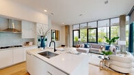 Located at 3130 Potomac Ave in Arlington, VA, this two-story residence offers a thoughtfully designed layout across two generously sized floors. The main level opens into a bright, open-plan kitchen and living area defined by dramatic floor-to-ceiling glass walls that flood the space with natural light and frame lush outdoor greenery. Exposed concrete columns add an industrial architectural accent against the otherwise crisp white interior palette and warm light oak hardwood flooring.

The kitchen is sleek and contemporary, featuring flat-front white cabinetry extending to the ceiling, a large waterfall-edge island with an undermount sink, a gas cooktop, and integrated stainless steel wall ovens. A hallway and entry foyer with large-format windows complete the main level.

The upper floor houses both bedrooms and two of the three bathrooms. The expansive primary suite offers direct access to outdoor views through floor-to-ceiling sliding glass doors, and includes a well-appointed en-suite bathroom finished in large-format neutral tiles, a floating white vanity, and a dedicated walk-in closet. The second bedroom is equally light-filled. All three bathrooms share a consistent modern aesthetic with matte black hardware and clean, minimalist finishes throughout.