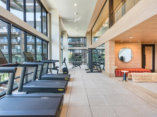 Gimnasio luminoso con equipos cardiovasculares y de fuerza de primera calidad, además de relajantes sillones en las inmediaciones. - Modera Reserve