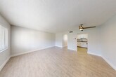 Located at 2727 N Andrews Ave in Wilton Manors, Florida, this efficiently designed single-floor unit offers a bright and cohesive living environment. Light wood-look plank flooring flows consistently throughout the space, complemented by crisp white walls and white baseboards that lend a clean, modern aesthetic.

The open living area is spacious relative to the overall footprint, featuring a ceiling fan with a brushed gold finish and a textured ceiling. Natural light enters through a wide window fitted with white horizontal blinds, offering a view of the surrounding greenery. The living area connects seamlessly to the kitchen, which is outfitted with white shaker-style cabinetry, granite countertops, a stainless steel sink, and stainless steel appliances including a range and microwave.

The bedroom includes two side-by-side closets with six-panel doors and a window that brings in additional natural light. The bathroom is appointed with a granite-topped vanity, an undermount sink, brushed nickel fixtures, a wall-mounted toilet, and a large mirror. A hallway connects the main living areas to the bedroom, bathroom, and closet. The unit's layout is functional and well-organized, making efficient use of its compact footprint in a desirable South Florida location.