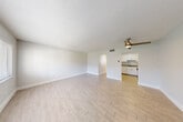 Located at 2727 N Andrews Ave in Wilton Manors, Florida, this efficiently designed single-floor unit offers a bright and cohesive living environment. Light wood-look plank flooring flows consistently throughout the space, complemented by crisp white walls and white baseboards that lend a clean, modern aesthetic.

The open living area is spacious relative to the overall footprint, featuring a ceiling fan with a brushed gold finish and a textured ceiling. Natural light enters through a wide window fitted with white horizontal blinds, offering a view of the surrounding greenery. The living area connects seamlessly to the kitchen, which is outfitted with white shaker-style cabinetry, granite countertops, a stainless steel sink, and stainless steel appliances including a range and microwave.

The bedroom includes two side-by-side closets with six-panel doors and a window that brings in additional natural light. The bathroom is appointed with a granite-topped vanity, an undermount sink, brushed nickel fixtures, a wall-mounted toilet, and a large mirror. A hallway connects the main living areas to the bedroom, bathroom, and closet. The unit's layout is functional and well-organized, making efficient use of its compact footprint in a desirable South Florida location.