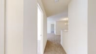 Located at 2456 Masons Ferry Dr in Herndon, Virginia, this single-level residence offers a straightforward, functional layout with a neutral color palette throughout. The interior is finished with plush wall-to-wall carpeting in the living, dining, and bedroom areas, while warm hardwood-style flooring runs through the kitchen and bathrooms, providing a clean contrast.

The galley-style kitchen is equipped with white appliances including a refrigerator and range, ample cabinetry, a double stainless steel sink with updated faucet, and light countertops. A dedicated door provides additional access from the kitchen. Adjacent to the kitchen, the dining area is anchored by an elegant brass chandelier and flows openly into the main living space.

The living room is generously sized, receiving ample natural light through large windows and a sliding glass door that opens to an outdoor patio. A hallway connects the living areas to the bedrooms, each of which features carpet flooring and well-sized windows that bring in natural light and treetop views.

Both bathrooms are finished with white tile surround tub-shower combinations, hardwood-style flooring, and classic panel doors with brass hardware. The overall ambiance is bright, clean, and move-in ready.