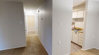 Located at 1449 Richland Road in Auburn, Alabama, this single-floor, one-bedroom, one-bathroom unit offers a practical and well-organized layout. The galley-style kitchen is outfitted with white cabinetry, warm butcher-block countertops, black appliances including a refrigerator, electric range, and dishwasher, all set atop wood-look flooring. The kitchen opens conveniently to a dedicated dining area, illuminated by a pendant light fixture overhead. The living room features neutral carpet and connects seamlessly to the rest of the unit via a central hallway. The spacious bedroom is carpeted and benefits from natural light through a large window with outdoor wooded views, and offers ample storage with two sets of bifold closet doors. The full bathroom includes a tiled tub-shower combination with a curtain rod, wood-look flooring, and clean, neutral finishes. A dedicated laundry area provides washer and dryer hookups along with an overhead shelf for added storage. Neutral gray walls, textured ceilings, and consistent flooring choices throughout give the unit a cohesive and move-in-ready appearance.