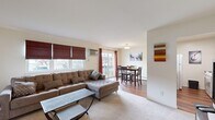 This well-appointed one-bedroom, one-bathroom residence in Middletown, NY offers a thoughtfully designed single-floor layout that maximizes both comfort and functionality. The open-concept living area greets you upon entry, featuring plush carpeting, large windows with roman shades that invite natural light, and a welcoming ambiance. A decorative wall mirror adds depth and brightness to the space.

The living area flows seamlessly into the dining room, which is highlighted by rich hardwood flooring, a sliding glass door with floor-to-ceiling drapes, and access to a private balcony with outdoor views. The adjacent kitchen is equipped with warm wood cabinetry, granite-style countertops, a kitchen island, and a full suite of appliances, making it both practical and inviting.

The spacious bedroom offers ample room, a wall of built-in louvered closets for generous storage, a window unit for climate control, and soft carpeting throughout. The bathroom features a tub/shower combination finished with elegant large-format gray marble-style tiles, lending a clean, modern aesthetic.

Connected by a functional hallway, this well-organized residence combines comfortable living with practical design in a convenient Middletown location.