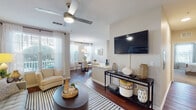 Located at 10880 Angel Fish Way in Jacksonville, Florida, this single-floor residence offers a well-designed layout with a seamless flow between living, dining, and kitchen areas. The open-concept living room features rich hardwood-style flooring, a ceiling fan, and large windows dressed with sheer curtains and blinds that allow generous natural light and views of the outdoors. The space comfortably accommodates a full seating arrangement and media setup.

Adjacent to the living area, the dining space benefits from its own set of bright windows and pendant lighting, creating an inviting setting for meals. The kitchen is well-appointed with rich dark cabinetry, stainless steel appliances including a refrigerator, range, and microwave, complemented by a tile backsplash and light countertops.

Both bedrooms are carpeted and fitted with ceiling fans, offering a cozy retreat. The primary bedroom provides direct access to a full bathroom featuring hardwood-style flooring, a tiled tub-shower combination, a vanity with dark wood cabinetry, and dual sinks. A dedicated in-unit laundry area with full-size washer and dryer adds everyday convenience. Neutral tones throughout the residence create a calm, cohesive ambiance.