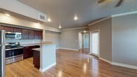 This well-appointed single-floor residence offers a thoughtfully designed open-concept layout that seamlessly connects the kitchen and living areas. The kitchen is a standout feature, showcasing rich dark-wood cabinetry with brushed nickel hardware, granite countertops, a peninsula breakfast bar, and stainless steel appliances including a dishwasher, range, and microwave. Light hardwood flooring flows throughout the main living spaces, complemented by neutral gray walls and clean white trim and crown molding.

The living area is generously sized, bathed in natural light from multiple windows and a glass-paneled exterior door, and finished with a ceiling fan and recessed lighting overhead. Each bedroom features plush wall-to-wall carpeting, a ceiling fan, and windows with blinds that allow for natural light. One bedroom includes access to a walk-in closet.

Two full bathrooms maintain the cohesive design aesthetic with dark wood vanity cabinetry, granite countertops, and tub-shower combinations finished with white subway tile surrounds and hardwood-style flooring. Throughout the unit, consistent use of quality materials, recessed lighting, and a neutral color palette create a clean, modern, and inviting atmosphere.