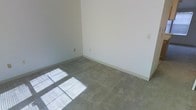 This two-floor residential space presents a clean, move-in-ready environment with a straightforward and functional layout. The interior is characterized by neutral, light-toned walls throughout, creating a bright and open atmosphere that serves as a versatile backdrop for any décor style. The flooring features wall-to-wall carpeting in a muted gray tone, providing comfort underfoot while lending a cohesive look across the rooms. Natural light filters in through the windows, casting soft light patterns across the carpet and further brightening the interior. The rooms are well-proportioned, offering ample space for furniture arrangement and everyday living. Standard electrical outlets are conveniently positioned along the walls, reflecting a practical and livable design. The clean lines of the white baseboards complement the neutral walls, giving each room a tidy, finished appearance. Spanning two floors, the space provides a natural separation between living areas, offering flexibility in how the layout can be utilized. Overall, the space combines simplicity with functionality, making it an ideal setting for those looking to personalize a clean, well-maintained home.