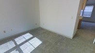 This two-floor residential space presents a clean, move-in-ready environment with a straightforward and functional layout. The interior is characterized by neutral, light-toned walls throughout, creating a bright and open atmosphere that serves as a versatile backdrop for any décor style. The flooring features wall-to-wall carpeting in a muted gray tone, providing comfort underfoot while lending a cohesive look across the rooms. Natural light filters in through the windows, casting soft light patterns across the carpet and further brightening the interior. The rooms are well-proportioned, offering ample space for furniture arrangement and everyday living. Standard electrical outlets are conveniently positioned along the walls, reflecting a practical and livable design. The clean lines of the white baseboards complement the neutral walls, giving each room a tidy, finished appearance. Spanning two floors, the space provides a natural separation between living areas, offering flexibility in how the layout can be utilized. Overall, the space combines simplicity with functionality, making it an ideal setting for those looking to personalize a clean, well-maintained home.
