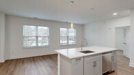 Located at 300 Main St in Madison, NJ, this thoughtfully designed residence at The Madison offers three bedrooms, two bathrooms, and a study across a single, well-organized floor. The open-concept living, dining, and kitchen area serves as the heart of the home, bathed in natural light from multiple large windows with views of the surrounding neighborhood. Light-toned hardwood flooring runs throughout, enhancing the bright, airy atmosphere created by the clean white walls and modern finishes.

The kitchen is a standout feature, centered around a large white quartz island with an integrated sink and pendant lighting above. Gray shaker-style cabinetry, a herringbone tile backsplash, stainless steel appliances including a gas range and French door refrigerator, and recessed lighting complete the contemporary design. The spacious primary bedroom includes its own dedicated closet with built-in shelving and hanging systems — one of five closets found throughout the unit, offering exceptional storage.

The bathrooms feature light tile flooring, gray vanities with quartz countertops, and large mirrors. A dedicated in-unit laundry room houses a full-size side-by-side washer and dryer. The overall aesthetic is clean, modern, and move-in ready.