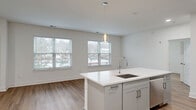 Located at 300 Main St in Madison, NJ, this thoughtfully designed residence at The Madison offers three bedrooms, two bathrooms, and a study across a single, well-organized floor. The open-concept living, dining, and kitchen area serves as the heart of the home, bathed in natural light from multiple large windows with views of the surrounding neighborhood. Light-toned hardwood flooring runs throughout, enhancing the bright, airy atmosphere created by the clean white walls and modern finishes.

The kitchen is a standout feature, centered around a large white quartz island with an integrated sink and pendant lighting above. Gray shaker-style cabinetry, a herringbone tile backsplash, stainless steel appliances including a gas range and French door refrigerator, and recessed lighting complete the contemporary design. The spacious primary bedroom includes its own dedicated closet with built-in shelving and hanging systems — one of five closets found throughout the unit, offering exceptional storage.

The bathrooms feature light tile flooring, gray vanities with quartz countertops, and large mirrors. A dedicated in-unit laundry room houses a full-size side-by-side washer and dryer. The overall aesthetic is clean, modern, and move-in ready.