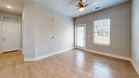 Located at 105 Stewart Dr in Easley, SC, this well-designed one-bedroom, one-bathroom unit offers a thoughtful layout across a single floor. The open-concept kitchen and living area serves as the heart of the home, where light-toned wood-style flooring flows seamlessly underfoot. The kitchen is outfitted with crisp white cabinetry, granite countertops, a peninsula with an integrated sink, pendant lighting, and black appliances including a refrigerator, range, and microwave. A hallway connects the main living space to the private bedroom, which features plush wall-to-wall carpeting, a ceiling fan with light fixture, a natural light-admitting window, and a generously sized double-door closet. The living room extends toward a glass exterior door flanked by windows, allowing abundant natural light and outdoor views to fill the room, further complemented by a ceiling fan overhead. The bathroom is finished with wood-look tile flooring, a white vanity with granite countertop, and clean, neutral wall tones that maintain the home's consistent modern aesthetic. Throughout the unit, neutral gray walls, white trim, and recessed lighting contribute to a bright, cohesive, and move-in-ready atmosphere.