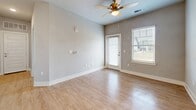 Located at 105 Stewart Dr in Easley, SC, this well-designed one-bedroom, one-bathroom unit offers a thoughtful layout across a single floor. The open-concept kitchen and living area serves as the heart of the home, where light-toned wood-style flooring flows seamlessly underfoot. The kitchen is outfitted with crisp white cabinetry, granite countertops, a peninsula with an integrated sink, pendant lighting, and black appliances including a refrigerator, range, and microwave. A hallway connects the main living space to the private bedroom, which features plush wall-to-wall carpeting, a ceiling fan with light fixture, a natural light-admitting window, and a generously sized double-door closet. The living room extends toward a glass exterior door flanked by windows, allowing abundant natural light and outdoor views to fill the room, further complemented by a ceiling fan overhead. The bathroom is finished with wood-look tile flooring, a white vanity with granite countertop, and clean, neutral wall tones that maintain the home's consistent modern aesthetic. Throughout the unit, neutral gray walls, white trim, and recessed lighting contribute to a bright, cohesive, and move-in-ready atmosphere.