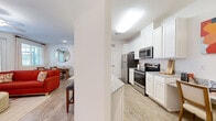 Located at 103 Inspiration Ave in Bluffton, SC, this single-floor, 2-bedroom, 3-bathroom residence offers a thoughtfully designed open-concept layout. Light wood-style flooring flows through the main living areas, complementing the bright, neutral palette throughout.

The kitchen is a functional highlight, featuring crisp white cabinetry with beadboard detailing, granite countertops, stainless steel appliances including a refrigerator, microwave, and range, and a peninsula with pendant lighting that provides additional seating and prep space.

The living and dining areas are bathed in natural light from large windows and a sliding glass door that opens to an outdoor balcony. The dining area is a welcoming space with ample room for a full dining set.

The primary bedroom offers a comfortable retreat with plush carpeting, natural light from well-appointed windows, and generous proportions. The second bedroom is equally cozy, also featuring carpeted floors and bright windows with outdoor views.

The bathrooms are finished with granite countertops, white cabinetry, and clean tile work. At least one bathroom features a full soaking tub and shower combination with built-in shelving. The overall ambiance is clean, modern, and move-in ready.
