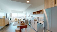 Located in the heart of Hollywood at 6390 De Longpre Ave, this thoughtfully designed single-floor residence combines contemporary finishes with an open, airy layout. The open-concept living and dining area is anchored by expansive floor-to-ceiling windows that frame breathtaking panoramic views of the Los Angeles cityscape, flooding the space with abundant natural light throughout the day. A distinctive exposed concrete column adds an industrial-modern architectural element that carries through the living room and into the bedroom.

The kitchen is well-appointed with light wood cabinetry, open shelving, a subway tile backsplash, stainless steel appliances including a full-size refrigerator, gas range, dishwasher, and built-in microwave — all complemented by light hardwood flooring that flows seamlessly through the main living areas.

The bedroom offers a serene retreat with wide windows showcasing the same sweeping city views, plush carpeting, and generous closet space. The bathroom features elegant marble-style tile flooring, a glass-enclosed walk-in shower with floor-to-ceiling tile, and a wood-framed vanity with stone countertop. Every detail of this residence reflects a refined, modern sensibility in one of Los Angeles' most vibrant neighborhoods.
