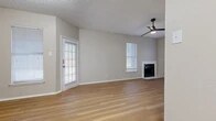 Located at 1021 Whisper Woods Cir in Fort Worth, TX, this single-story, one-bedroom, two-bathroom home offers a thoughtfully designed layout with a warm, contemporary aesthetic. Light-toned wood-look flooring runs throughout the entire home, creating a cohesive and inviting atmosphere.

The open-concept living room is bright and airy, featuring multiple windows with white plantation shutters that allow natural light to fill the space. A classic fireplace with a clean white surround serves as a focal point, while a modern ceiling fan with a sleek black finish adds both style and function. The living area flows seamlessly into the kitchen and dining space, which is connected via a pass-through opening. The galley-style kitchen is equipped with dark cabinetry, a refrigerator, and light stone countertops.

The bedroom is comfortably sized, featuring vaulted ceilings, a tall window for natural light, and neutral wall tones that complement the warm flooring. The two bathrooms are well-appointed; one includes a granite-topped vanity with black fixtures and a tub-shower combination with white tile surround, while the second features a full soaking tub with white tile walls. Multiple hallways provide practical connectivity throughout the home, completing this efficiently designed residence.
