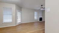 Located at 1021 Whisper Woods Cir in Fort Worth, TX, this single-story, one-bedroom, two-bathroom home offers a thoughtfully designed layout with a warm, contemporary aesthetic. Light-toned wood-look flooring runs throughout the entire home, creating a cohesive and inviting atmosphere.

The open-concept living room is bright and airy, featuring multiple windows with white plantation shutters that allow natural light to fill the space. A classic fireplace with a clean white surround serves as a focal point, while a modern ceiling fan with a sleek black finish adds both style and function. The living area flows seamlessly into the kitchen and dining space, which is connected via a pass-through opening. The galley-style kitchen is equipped with dark cabinetry, a refrigerator, and light stone countertops.

The bedroom is comfortably sized, featuring vaulted ceilings, a tall window for natural light, and neutral wall tones that complement the warm flooring. The two bathrooms are well-appointed; one includes a granite-topped vanity with black fixtures and a tub-shower combination with white tile surround, while the second features a full soaking tub with white tile walls. Multiple hallways provide practical connectivity throughout the home, completing this efficiently designed residence.