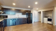 Located at 4602 Cottage Grove Rd in Madison, Wisconsin, this single-floor unit offers a clean, modern aesthetic throughout. The open-concept living area features light wood-tone luxury vinyl plank flooring and a ceiling fan, with a large sliding glass door framed by vertical blinds that fills the space with natural light and provides outdoor views. The kitchen is a standout feature, outfitted with rich, dark espresso-toned cabinetry, light granite-style countertops, and black appliances including a refrigerator, range, dishwasher, and microwave. Recessed lighting illuminates the kitchen, which flows seamlessly into the main living area. The bedrooms are carpeted for comfort, each with a ceiling fan and windows fitted with horizontal blinds that allow for natural light. A walk-in closet is accessible from the bedroom hallway, providing generous storage. The bathroom is well-appointed with a dual-sink vanity featuring matching dark cabinetry, a wide mirror with overhead lighting, a tub-shower combination, and wood-look flooring that ties the space together cohesively. Throughout the unit, neutral wall tones and consistent finishes create a fresh, move-in-ready environment well-suited for comfortable everyday living.