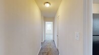 Located in Towson, MD, this single-floor residence offers four bedrooms, one bathroom, and a kitchen connected by three hallways. The layout is straightforward and functional, with neutral cream-toned walls and plush carpeting throughout the bedroom areas that create a cohesive, understated aesthetic.

The primary bedroom is the most expansive of the four, featuring three windows that invite abundant natural light and offer pleasant outdoor views of the surrounding greenery. The remaining bedrooms are comfortably sized with carpeted floors and windows that maintain a bright, airy feel throughout.

The kitchen is well-equipped, showcasing rich dark wood cabinetry, light granite-style countertops, hardwood flooring, and black appliances including an electric range with overhead ventilation. A stainless steel sink and dishwasher round out the practical amenities, with a window above the counter providing additional natural light.

The bathroom is finished with classic white subway tile wainscoting, a wood-toned vanity with a white countertop, a mirrored medicine cabinet, and a window that keeps the space feeling open and fresh.

Connecting hallways are carpeted and ceiling-lit, providing smooth transitions between rooms. Overall, the space offers a clean, move-in ready environment with practical finishes throughout.