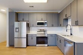 Located at 4200 N Carlin Springs Rd in Arlington, VA, this one-bedroom, one-bathroom unit offers a well-planned layout across a single floor. The combined living and dining area is bright and open, featuring light hardwood-style flooring, a ceiling fan, and a large window that fills the space with natural light and offers outdoor views. The kitchen is thoughtfully designed with gray cabinetry, white countertops, a subway tile backsplash, and a full suite of stainless steel appliances including a refrigerator with ice and water dispenser, range, built-in microwave, and dishwasher. A skylight adds additional brightness to the kitchen area. The bedroom is carpeted for comfort and includes a sliding-door closet, providing practical storage. A dedicated hallway closet offers additional storage space, and an in-unit laundry area adds everyday convenience. The bathroom is finished with large-format tile, a soaking tub with a tiled surround, matte black fixtures, and a gray vanity with a white countertop. Clean white walls and consistent finishes throughout give the unit a cohesive, modern feel.