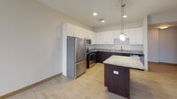 Located in the heart of downtown Toledo at N St Clair Street, this single-floor residence offers a well-designed layout with modern finishes throughout. The kitchen serves as a standout centerpiece, boasting two-tone cabinetry with crisp white upper cabinets and rich dark espresso lower cabinets, granite countertops, a central island with pendant lighting, and a full suite of stainless steel appliances including a refrigerator, range, microwave, and dishwasher. Light wood-style flooring runs through the kitchen and main living areas, lending warmth and continuity to the space. The living and sleeping areas are carpeted for comfort and feature dramatic floor-to-ceiling windows that frame sweeping panoramic views of the Toledo skyline, flooding the interior with natural light. The bathrooms are finished in a clean, contemporary style, each featuring dark espresso vanities, tile-style flooring, and a full tub-shower combination. The overall ambiance is polished and modern, with a neutral color palette that creates a bright, airy atmosphere throughout. This elevated urban residence combines functional design with high-quality finishes, offering a refined living experience in the midst of downtown Toledo.