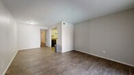 Located in Austin's vibrant 78704 corridor, this two-bedroom, one-bathroom residence offers a practical and comfortable single-level layout. Rich, dark wood-style flooring flows throughout the main living area, creating a warm and cohesive aesthetic that pairs well with the neutral gray wall tones and clean white trim. The open living room is bathed in natural light through a large sliding glass door fitted with vertical blinds, which leads to an outdoor area and gives the space an airy, connected feel.

The kitchen is thoughtfully laid out in a U-shaped configuration, featuring white cabinetry, a white subway tile backsplash, and black appliances including a range, refrigerator, and dishwasher. A built-in sink and ample counter space make it a fully functional cooking area. Wood-style flooring continues here, maintaining design consistency throughout.

The primary bedroom is generously proportioned, with its own sliding glass door access to the outdoors and a ceiling fan for added comfort. Additional bedrooms are well-sized with large windows that let in natural light. A dedicated walk-in closet offers built-in wire shelving on both sides, providing excellent storage capacity. A hallway connects the bedrooms and bathroom, completing this efficiently designed and move-in-ready home.